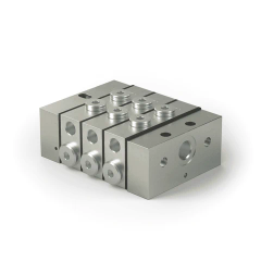 Silberfarbener Metallblock mit mehreren Bohrungen und Schrauben