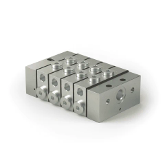 Silberfarbener Metallblock mit mehreren Bohrungen und Schrauben